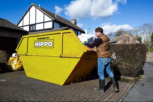 Large yellow skip being filled by man