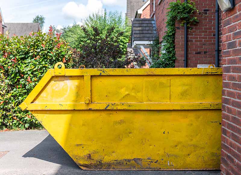 Skip placed to side of house