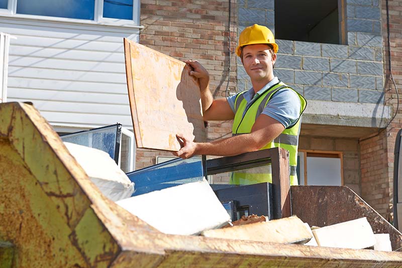 Person loading a skip with waste