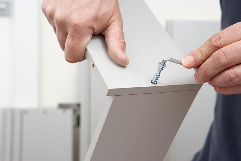 A person disassembling furniture with an allen key