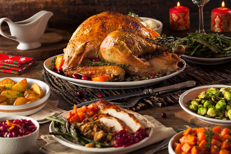 A Christmas dinner with turkey, trimmings and a jug of gravy on a rustic dining table