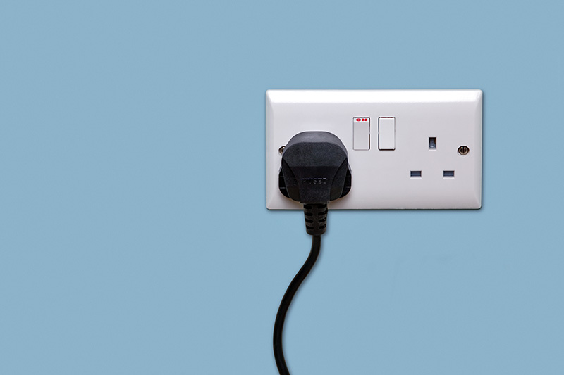 A UK electric plug socket with a plug plugged in