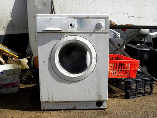 An old washing machine with a collection of waste for recycling