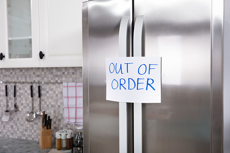 A large fridge freezer with an out of order note on the door