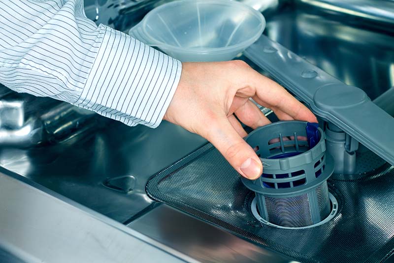 Clean dishwasher filter being placed in dishwasher