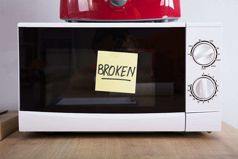 Microwave with a sticky note stating it is broken